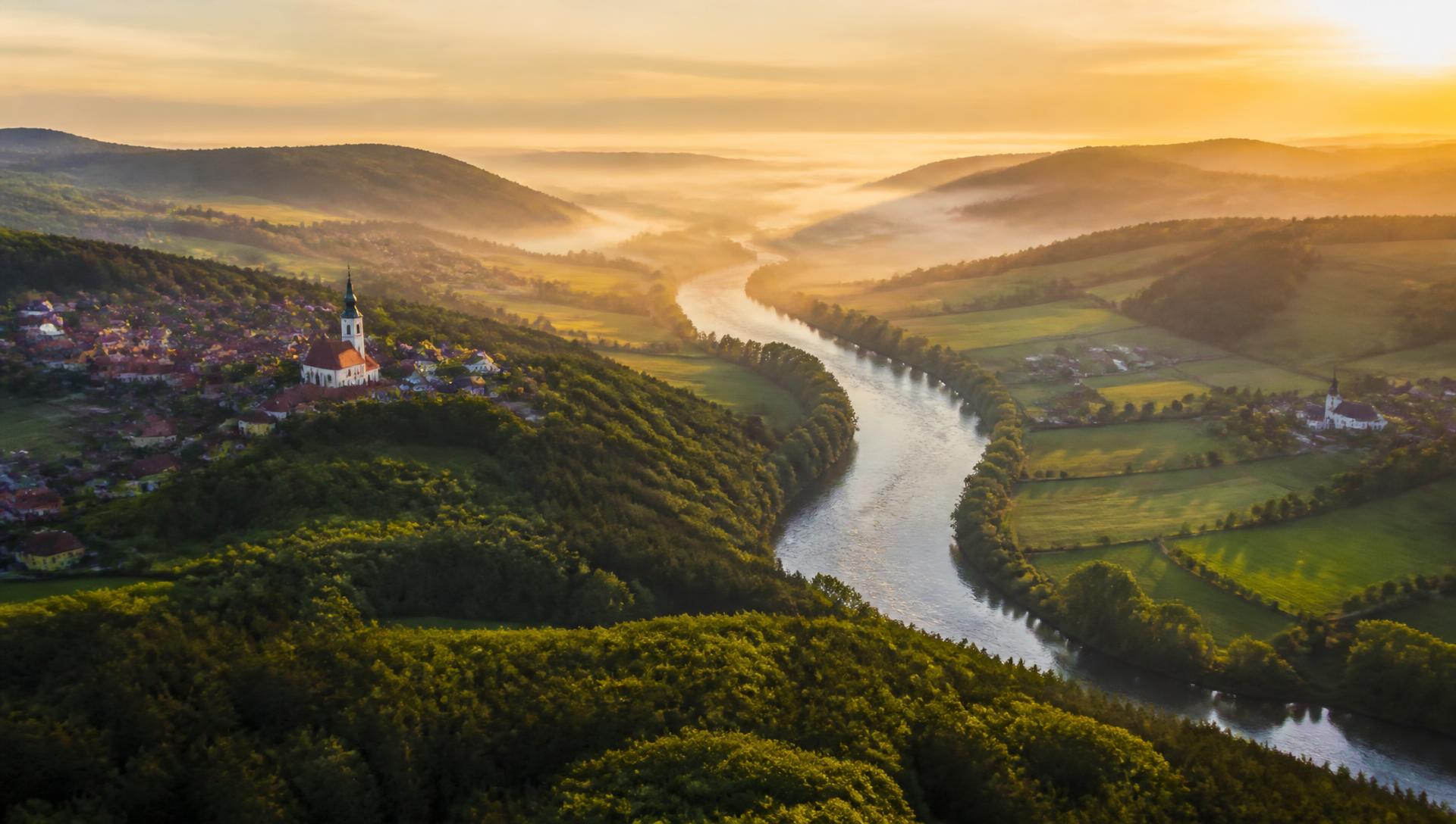 Luftaufnahme der Donau mit Dörfern und Feldern in der Morgensonne